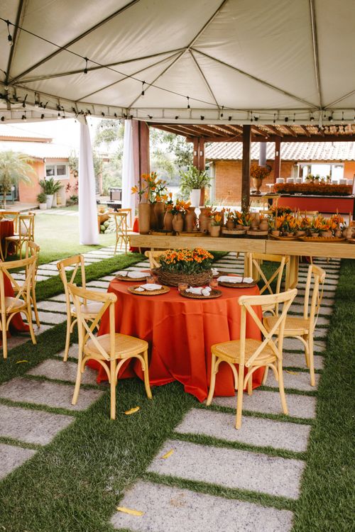 Free Chic outdoor wedding reception featuring terracotta decor and vibrant orange accents under a tent. Stock Photo