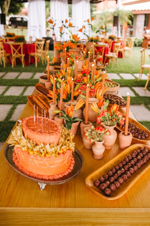 Free Vibrant wedding setup featuring an orange cake with terracotta decor and floral arrangements. Stock Photo