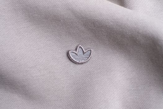Detailed view of fabric texture with an embroidered logo in a neutral color scheme.