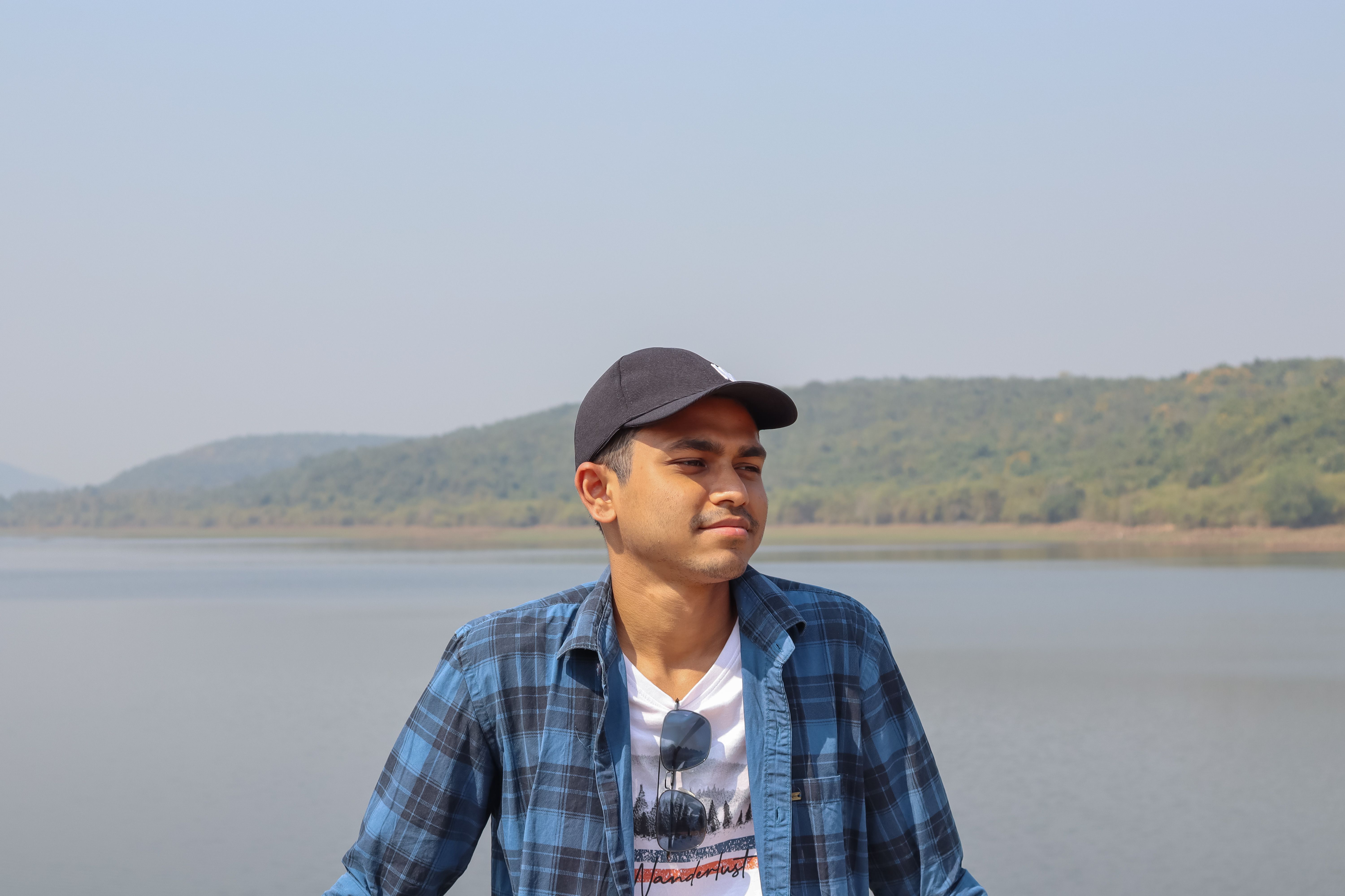 Young man enjoying tranquility by a calm lake in Odisha, India, surrounded by nature.