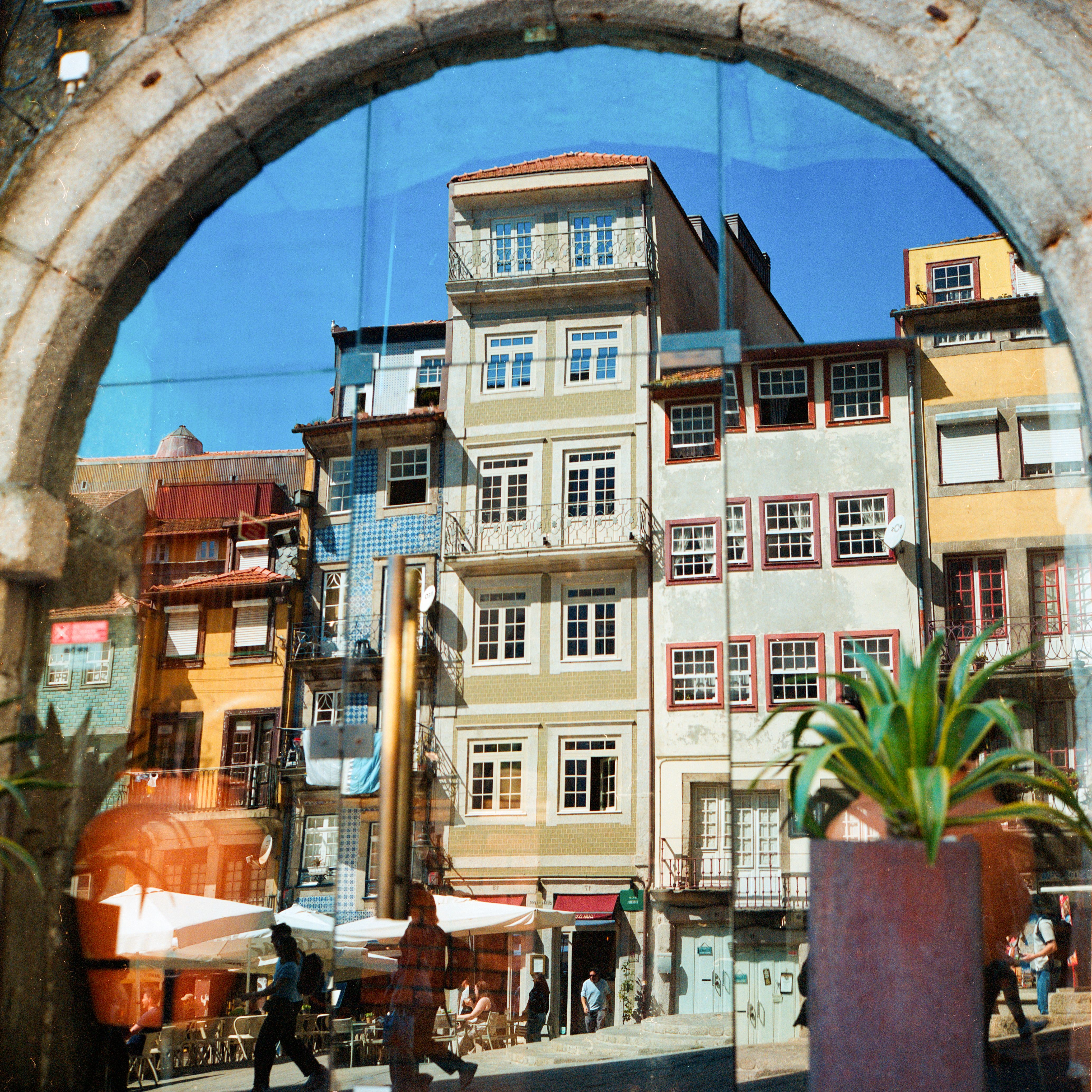 A vibrant street scene in Porto reflects through an archway, capturing the charm of colorful buildings.