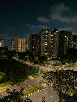 High-rise buildings at night with illuminated windows and street lights.