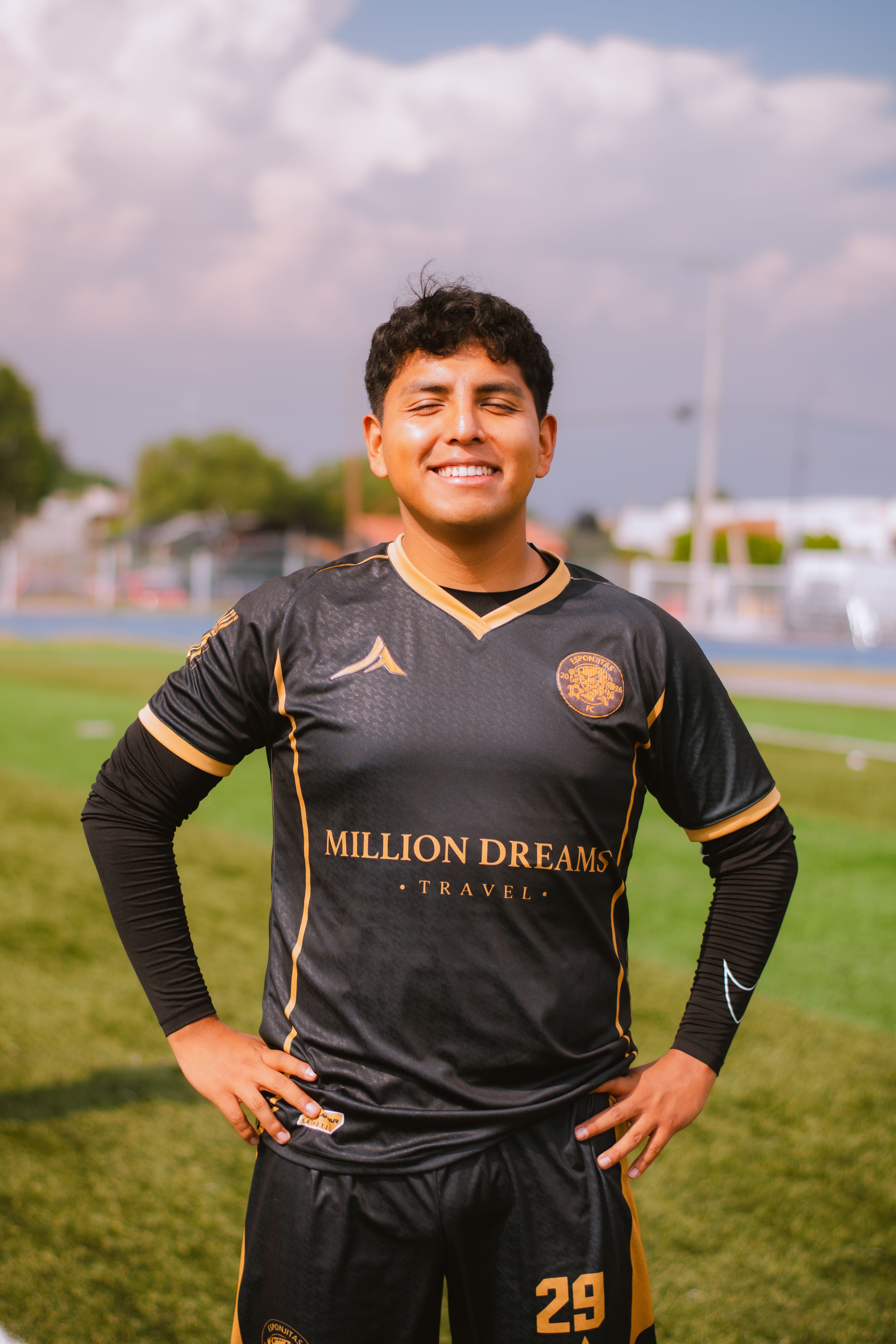 Happy soccer player posing confidently on a sunny day at the field.