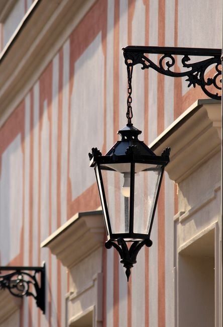 Charming vintage street lamp adorning a classic facade with striped design, capturing elegant architectural details.