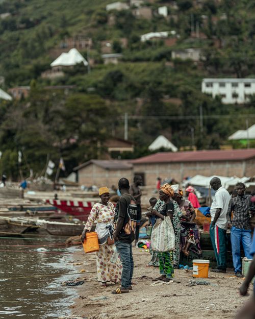 Free Vibrant scene of a local lakeside market with people interacting by the water. Stock Photo