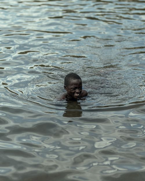 Free A young boy delightfully swimming in serene river waters, capturing the essence of pure joy and nature. Stock Photo