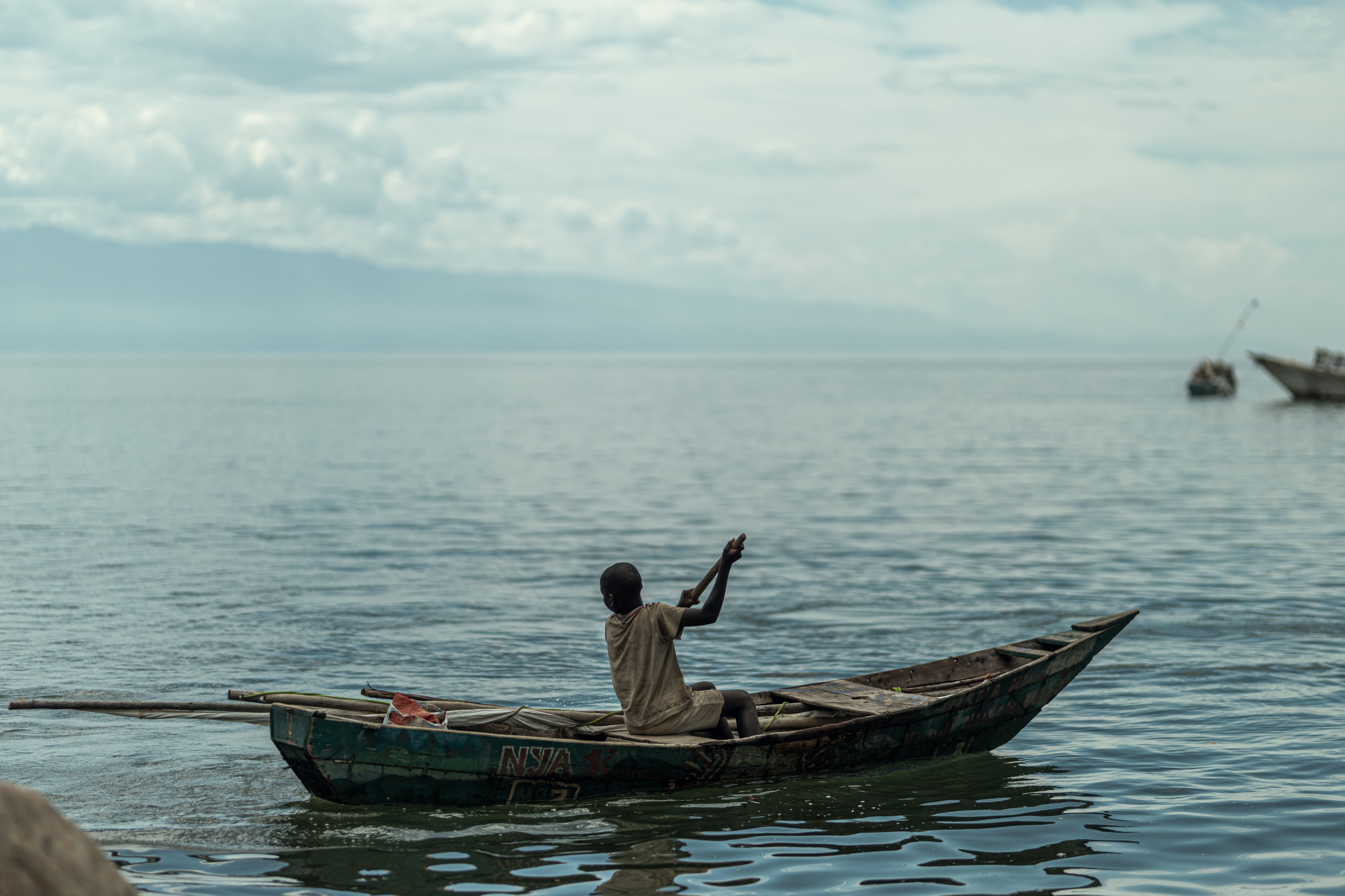 Solitary fisherman in wooden boat on tranquil lake, Burundi