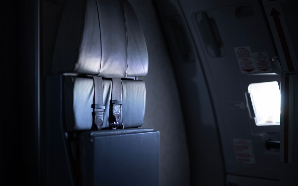 Moody view of an airplane interior focusing on the emergency exit with low lighting.