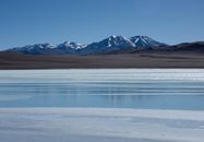 Serene winter landscape of snow-capped mountains and a frozen lake in Catamarca, Argentina.