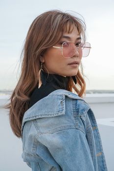 身着户外牛仔夹克和太阳镜的时尚女性肖像