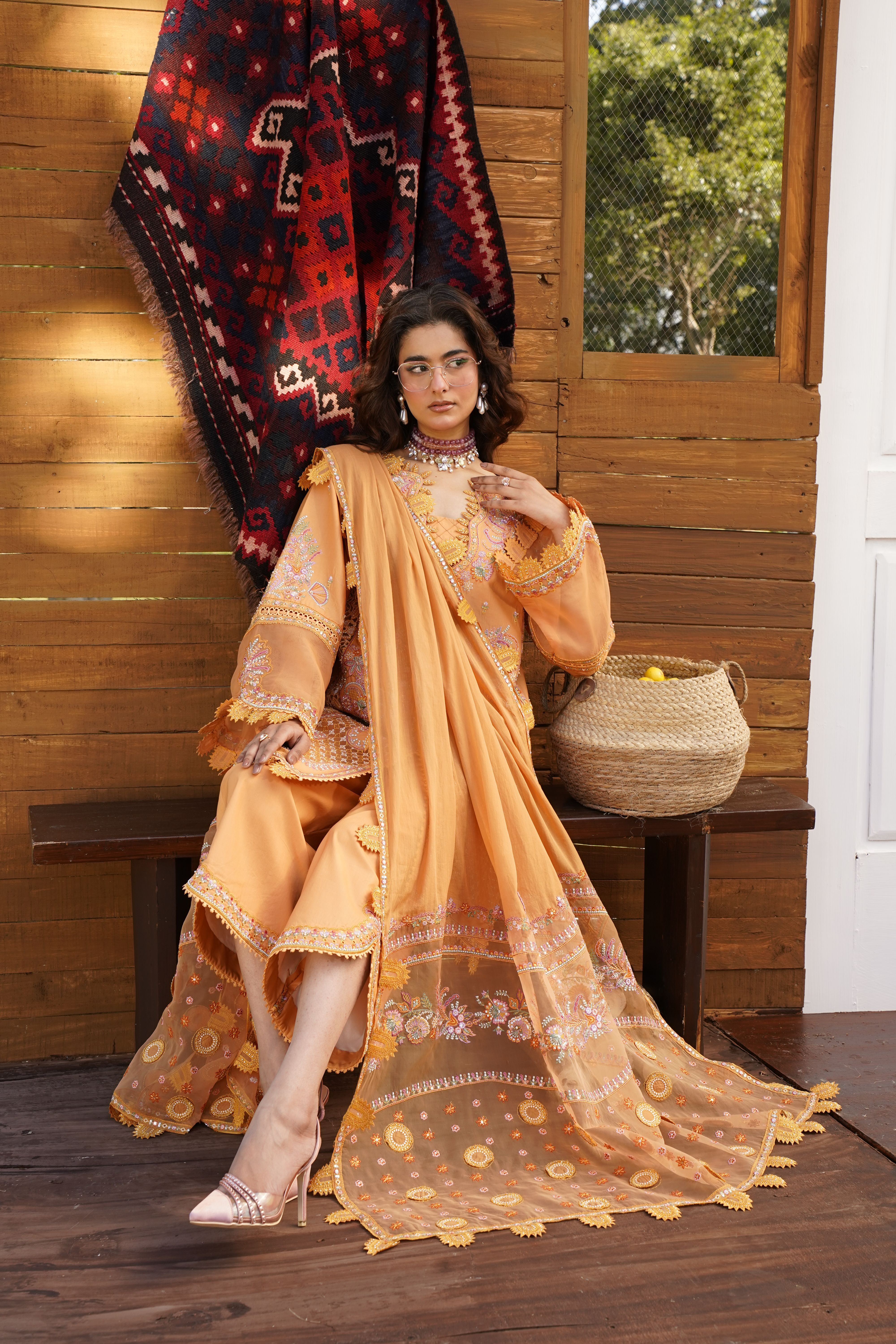 Fashion model in an elegant orange dress in a stylish indoor setting, ideal for fashion editorial use.