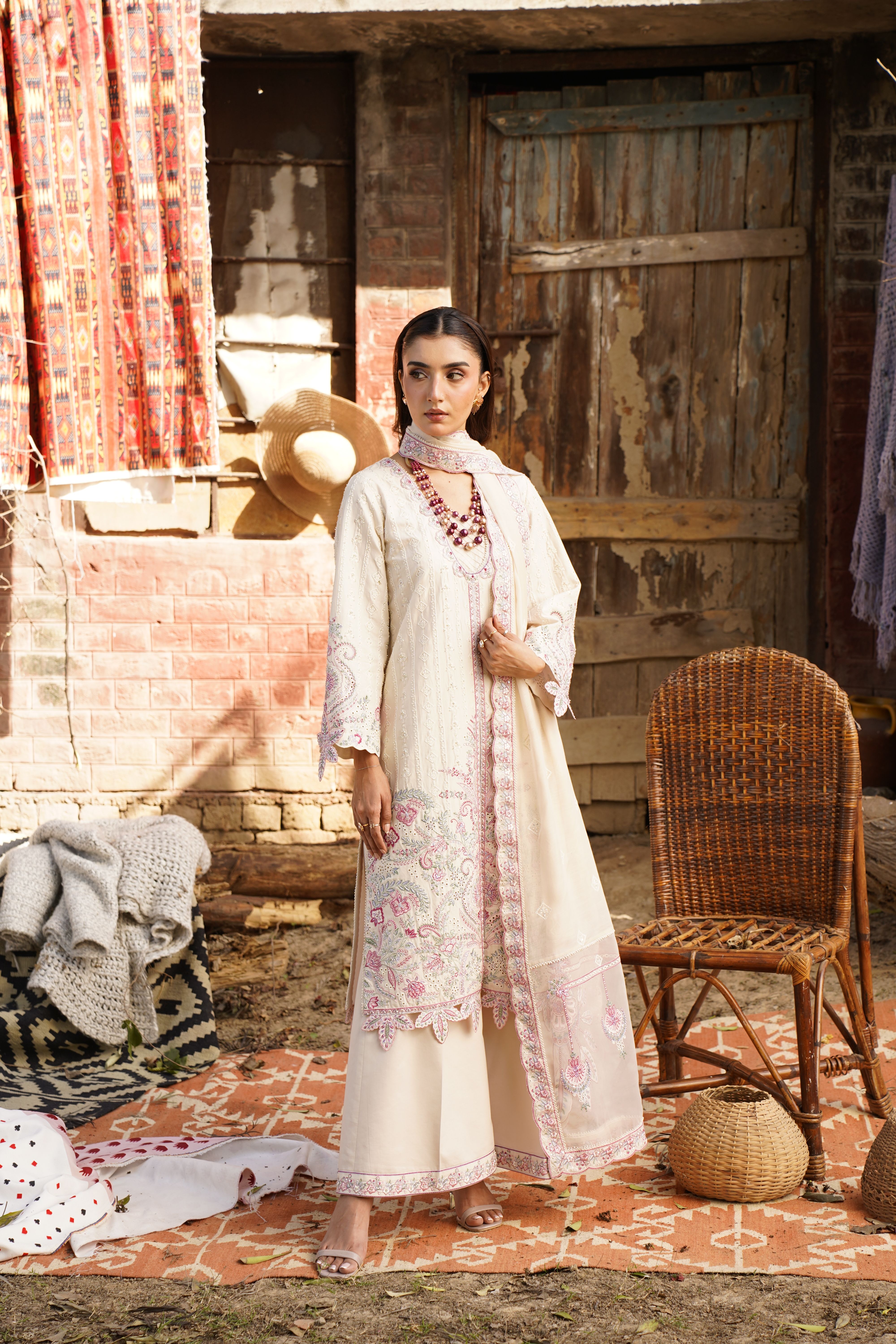 Fashion shoot featuring a female model in traditional attire against a rustic backdrop.