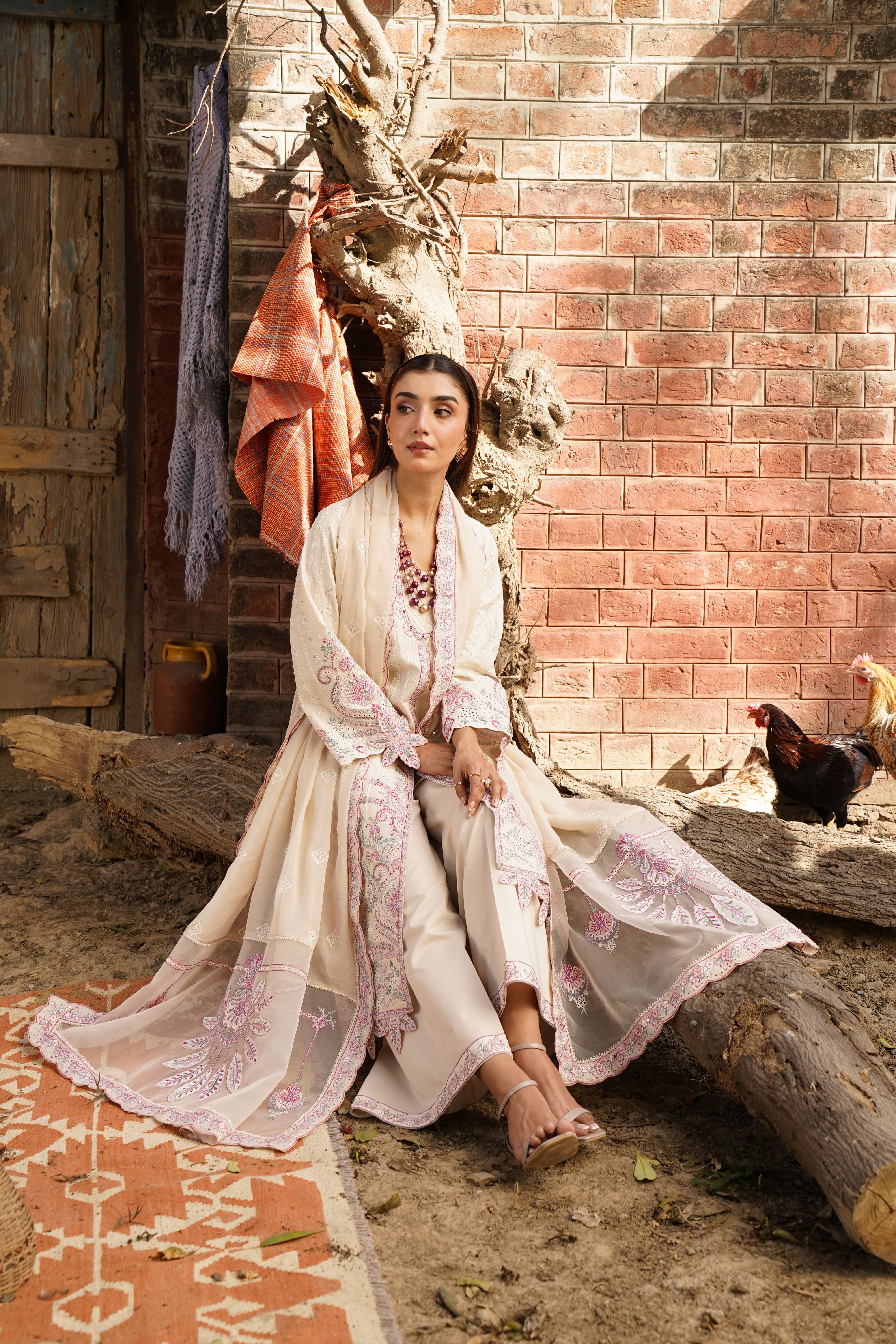 A woman models elegant traditional attire in a rustic outdoor setting, exuding style and grace.