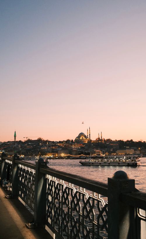 Free Scenic view of Istanbul skyline and Galata Bridge at sunset, featuring iconic architecture and calm waters. Stock Photo