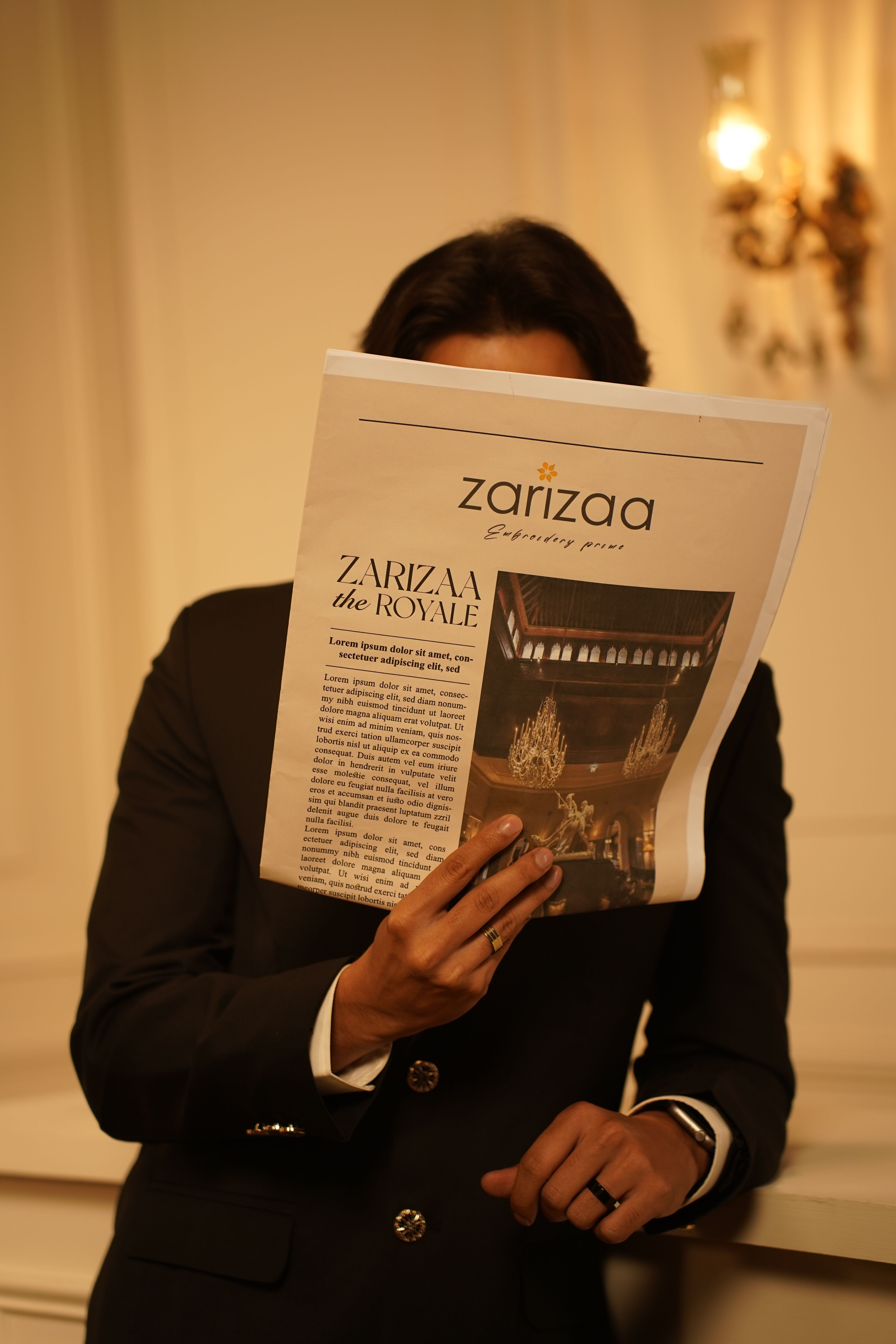 Stylish man in formal attire reading a fashion magazine indoors, exuding sophistication.
