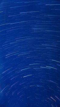 Dazzling long exposure of star trails against a deep blue night sky.