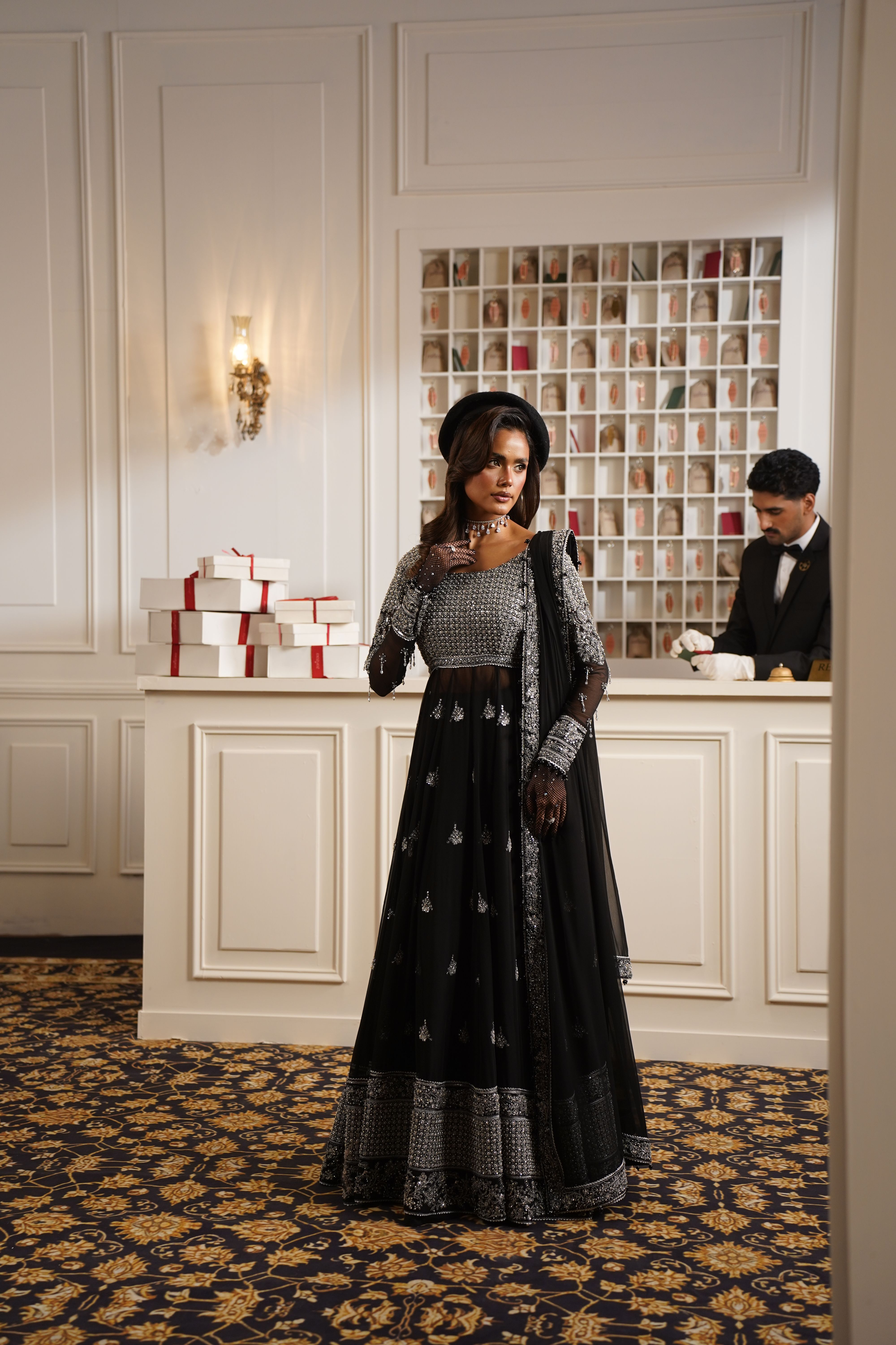 A glamorous female model poses in a luxurious setting, showcasing elegant fashion.