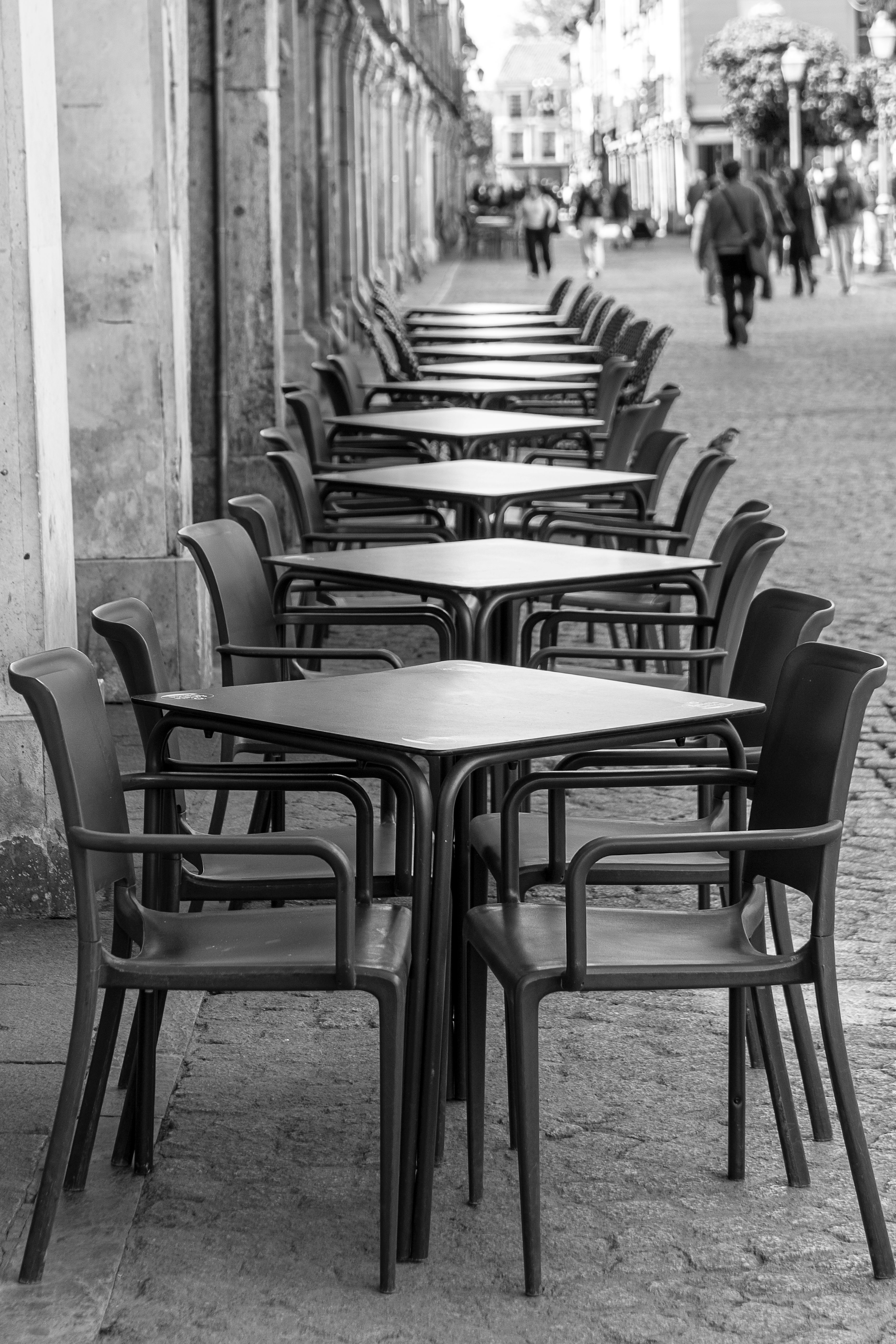 Monochrome view of empty outdoor café tables in Alcalá de Henares, Spain.
