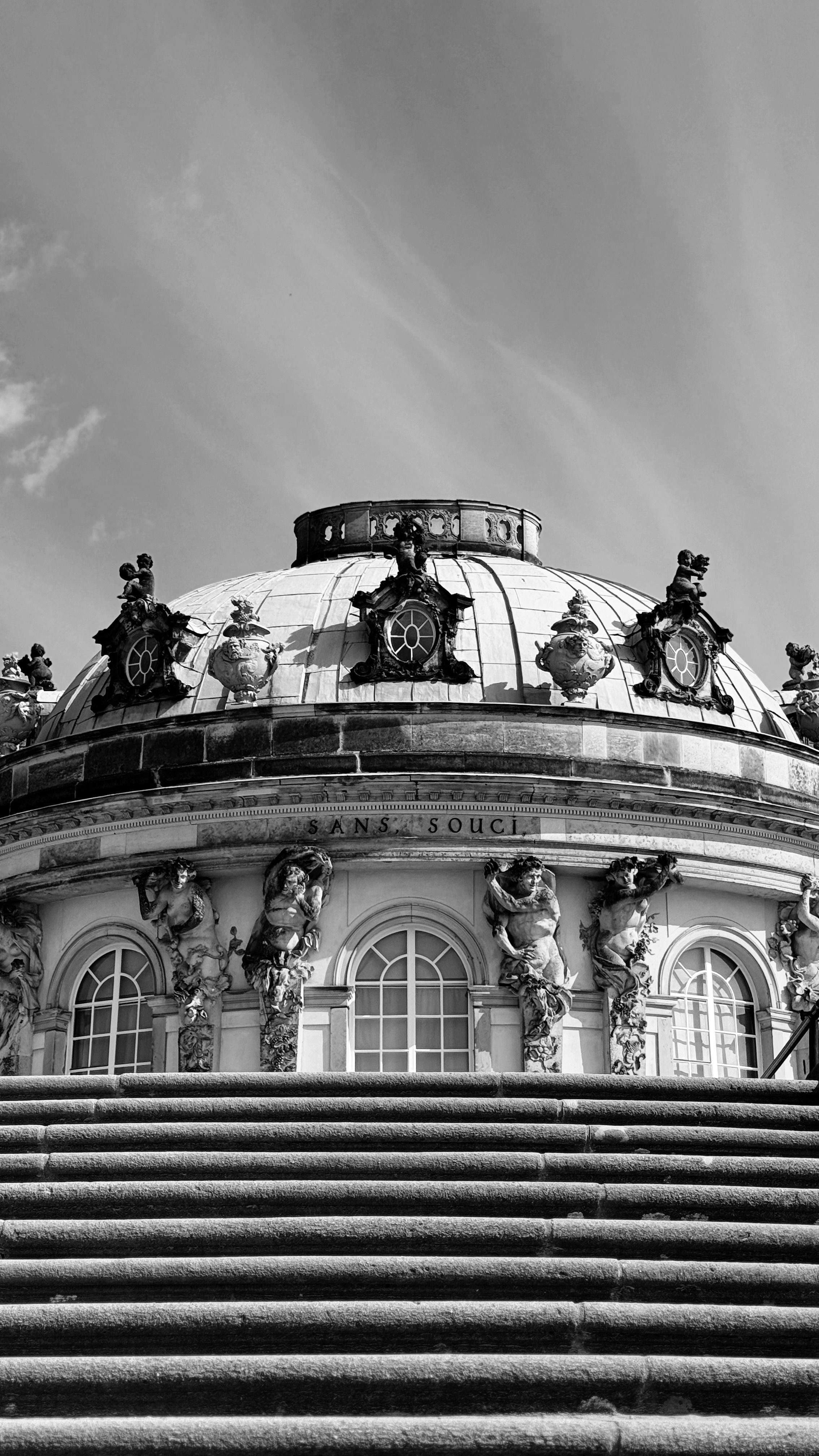 Black and white photo of Sanssouci Palace dome with intricate sculptures in Potsdam, Germany.
