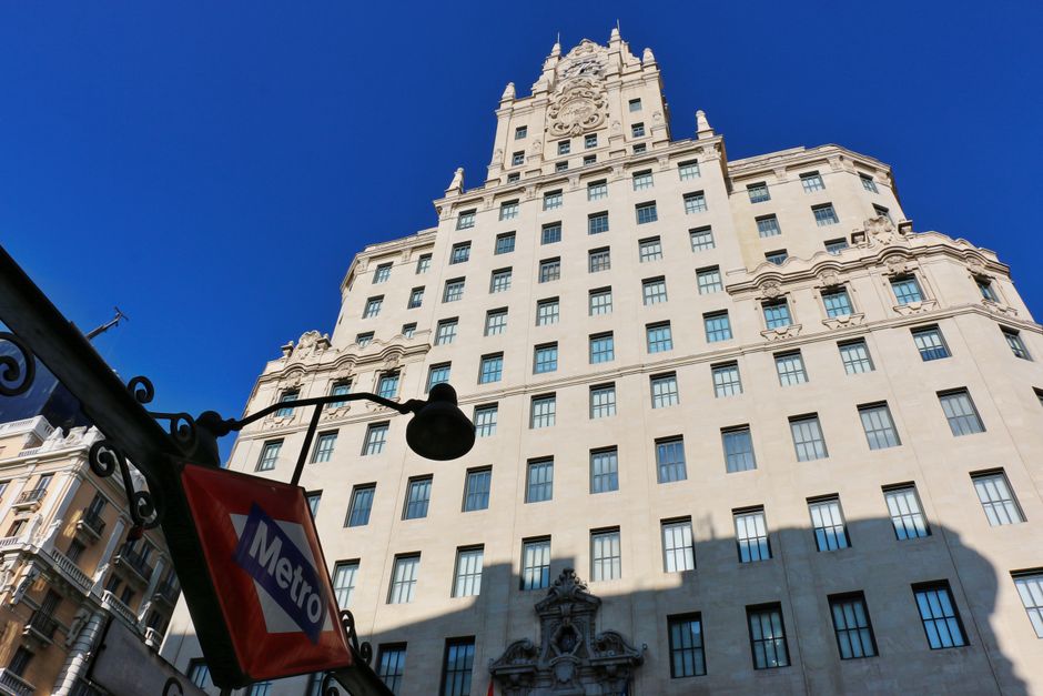 Edificio histórico de gran altura con letrero de metro bajo un cielo azul despejado.
