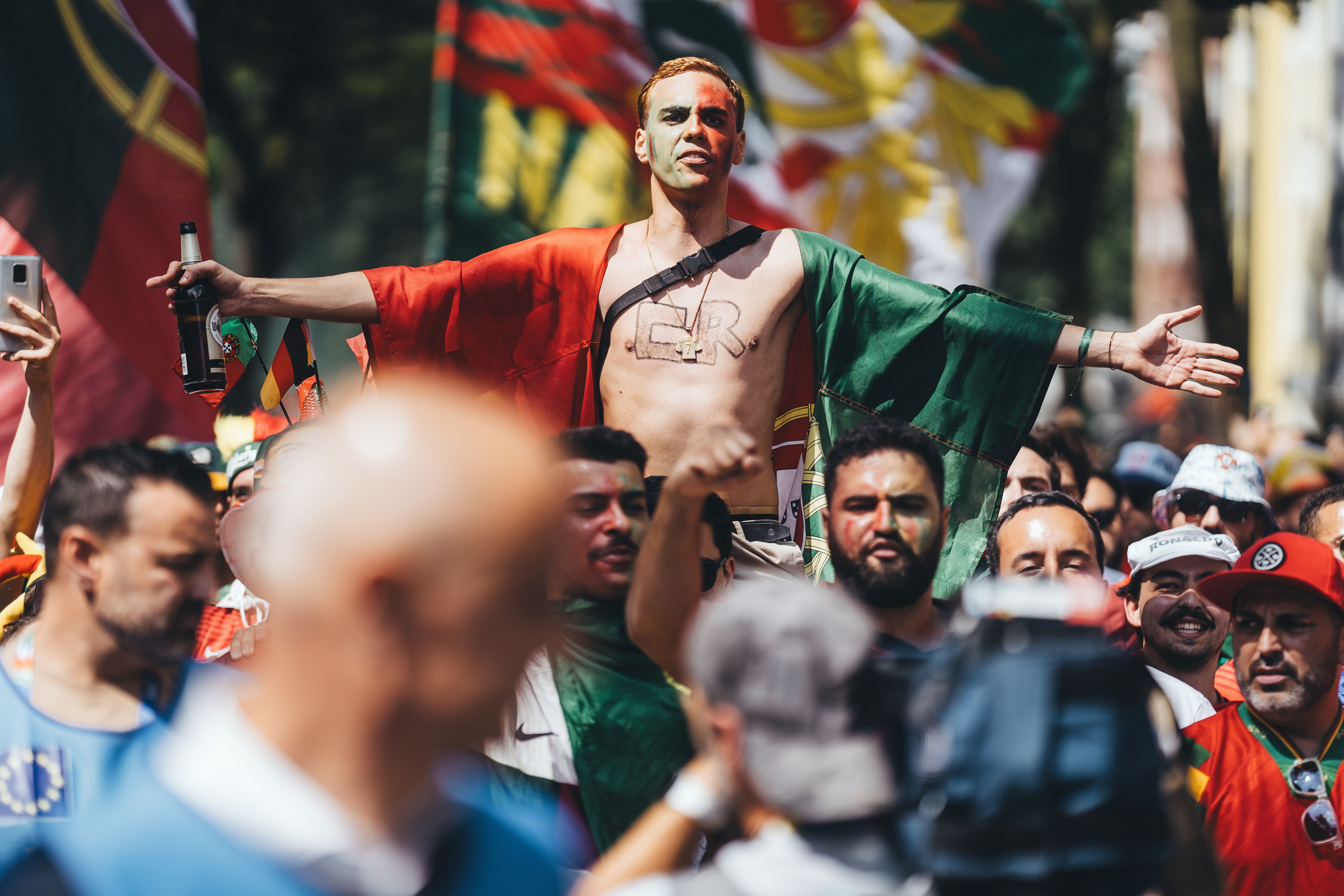 Energetic crowd at a street parade with a man holding a flag. Celebratory atmosphere.
