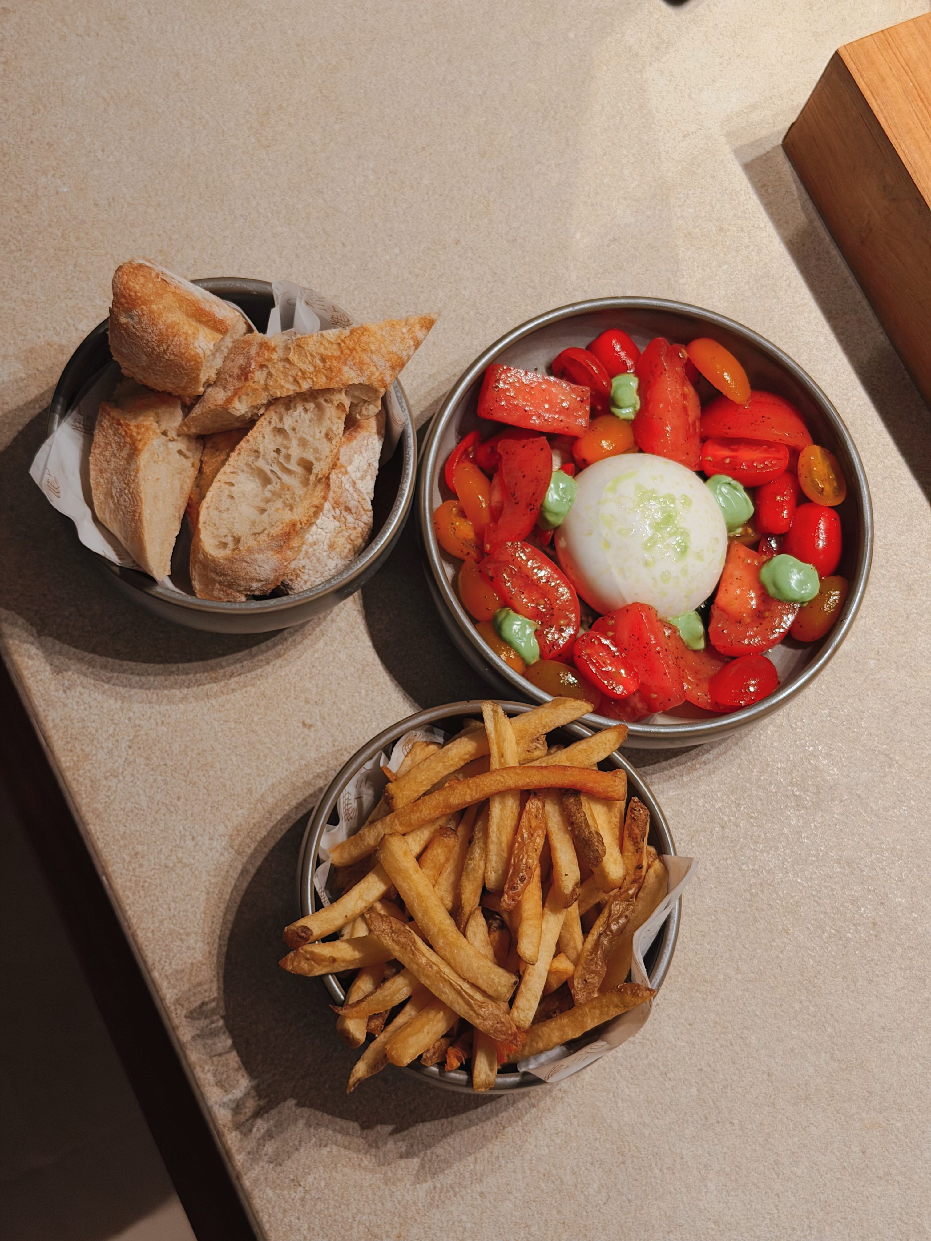 Tasty combination of rustic bread, fresh burrata salad, and crispy fries on a stone surface.