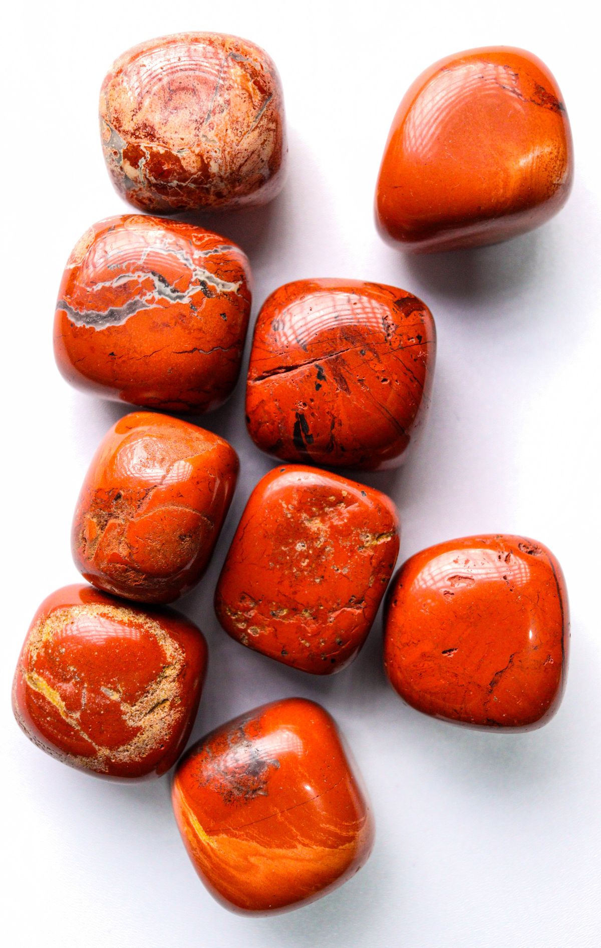Bright polished red jasper stones arranged on a white background
