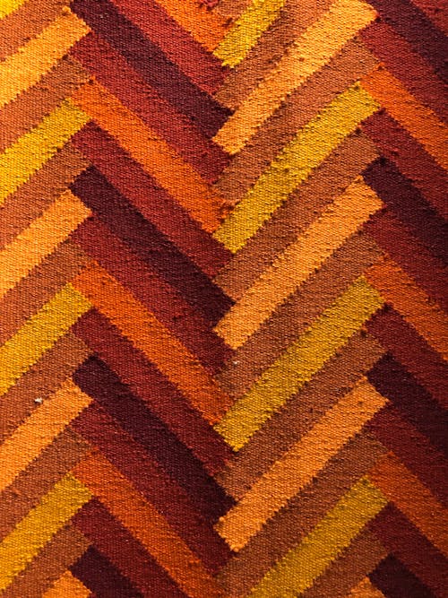 Closeup of textured background of bright fabric made of natural material representing symmetrical lines with different red and brown color shades