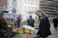 一位穿着紫罗兰色外套的女人在户外市场挑选鲜花时微笑着