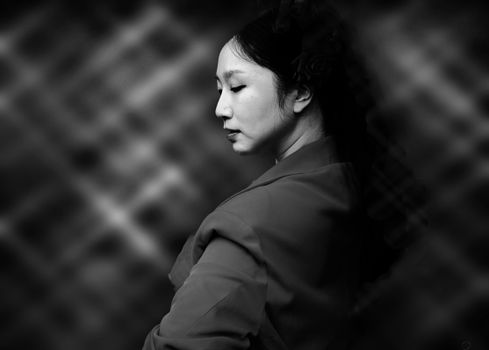 Sophisticated black and white portrait of a woman in profile with a blurred background, conveying elegance and poise.