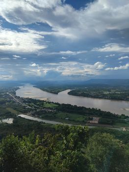 A breathtaking view of a river winding through a lush landscape under a dramatic, cloudy sky. - Fotografer Sidoarjo