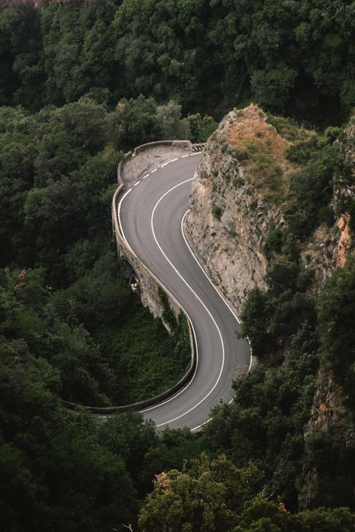 Free A stunning aerial view of a winding road through lush green hills, perfect for travel inspiration. Stock Photo