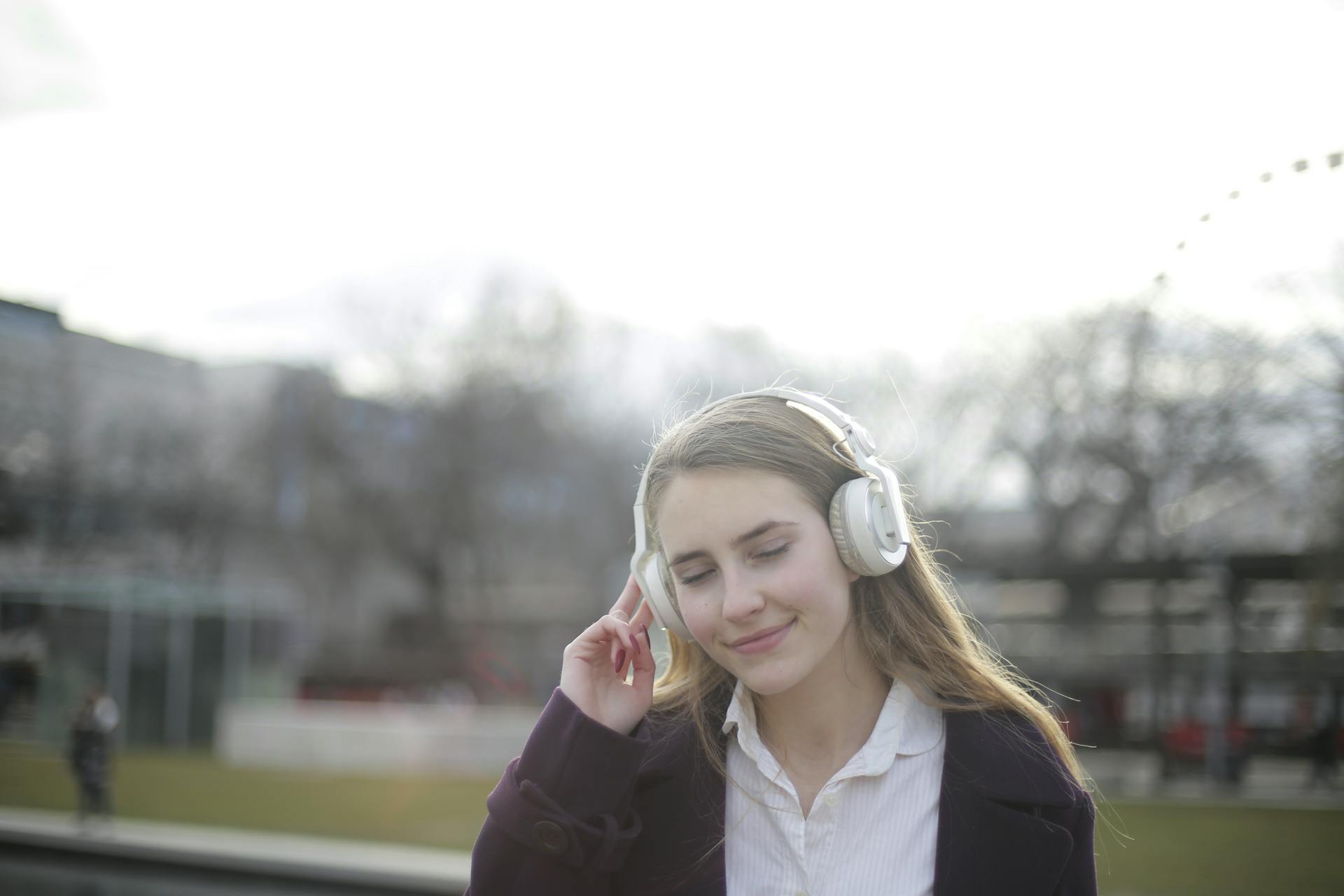 Young woman enjoying music outdoors with headphones, exuding relaxation and happiness.