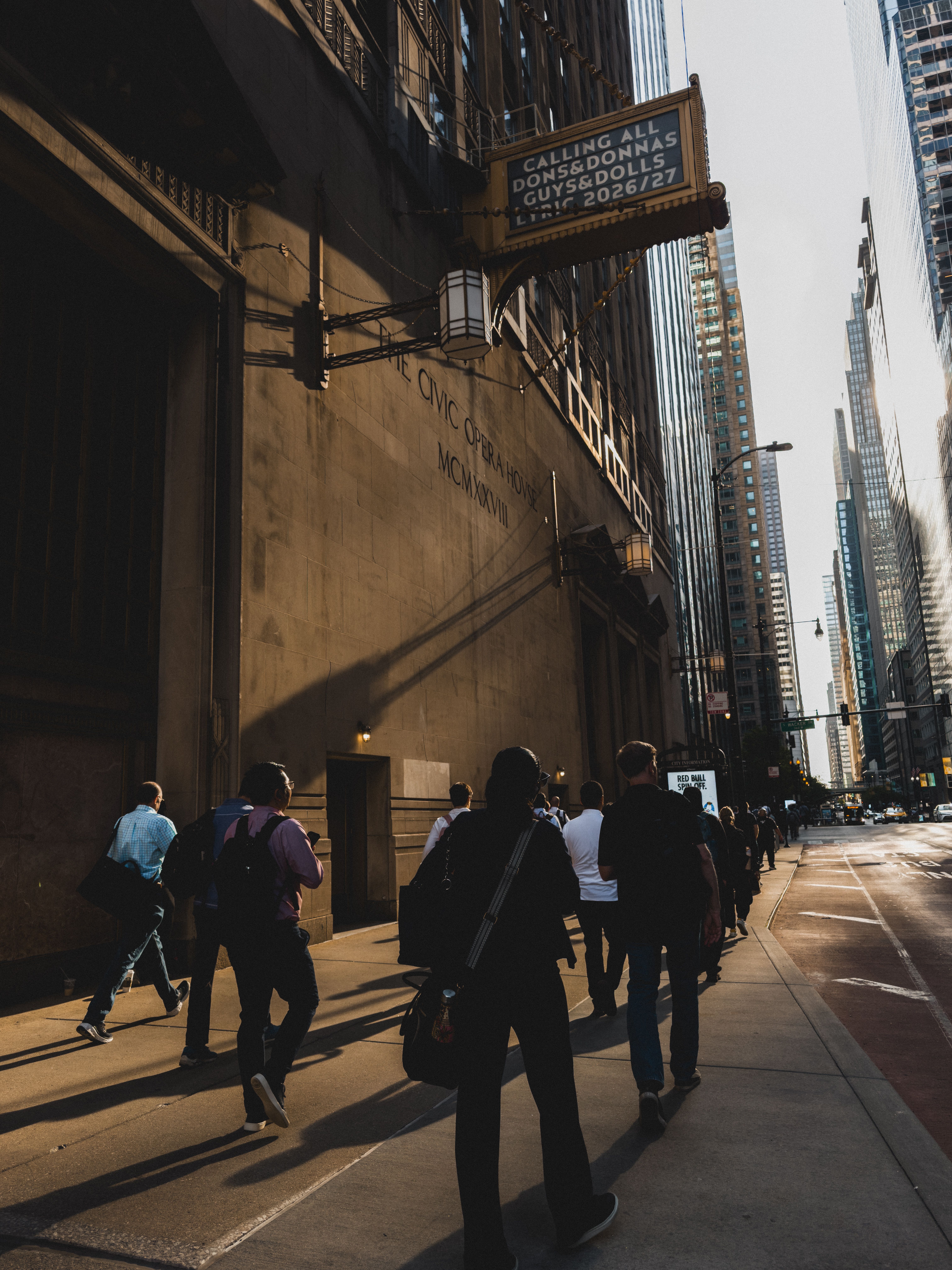 A lively city scene with people walking along a Chicago street at sunset with skyscrapers.