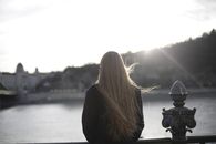 日落时分，一位身着紫罗兰色外套的女人在风景秀丽的河边留下背影