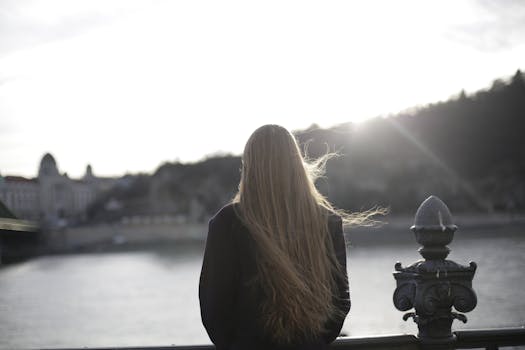 日落时分，一位身着紫罗兰色外套的女人在风景秀丽的河边留下背影