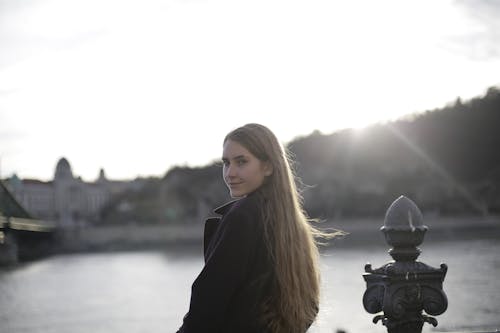 Woman in Violet Coat Standing Near Body of Water