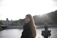 日落时分，一位长发年轻女子在海滨微笑，场景迷人而宁静