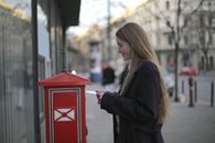 Woman in Black Coat Standing Beside Red Telephone Booth