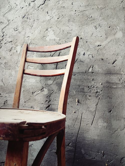 Free Old wooden chair with patina against a rustic textured concrete wall. Stock Photo