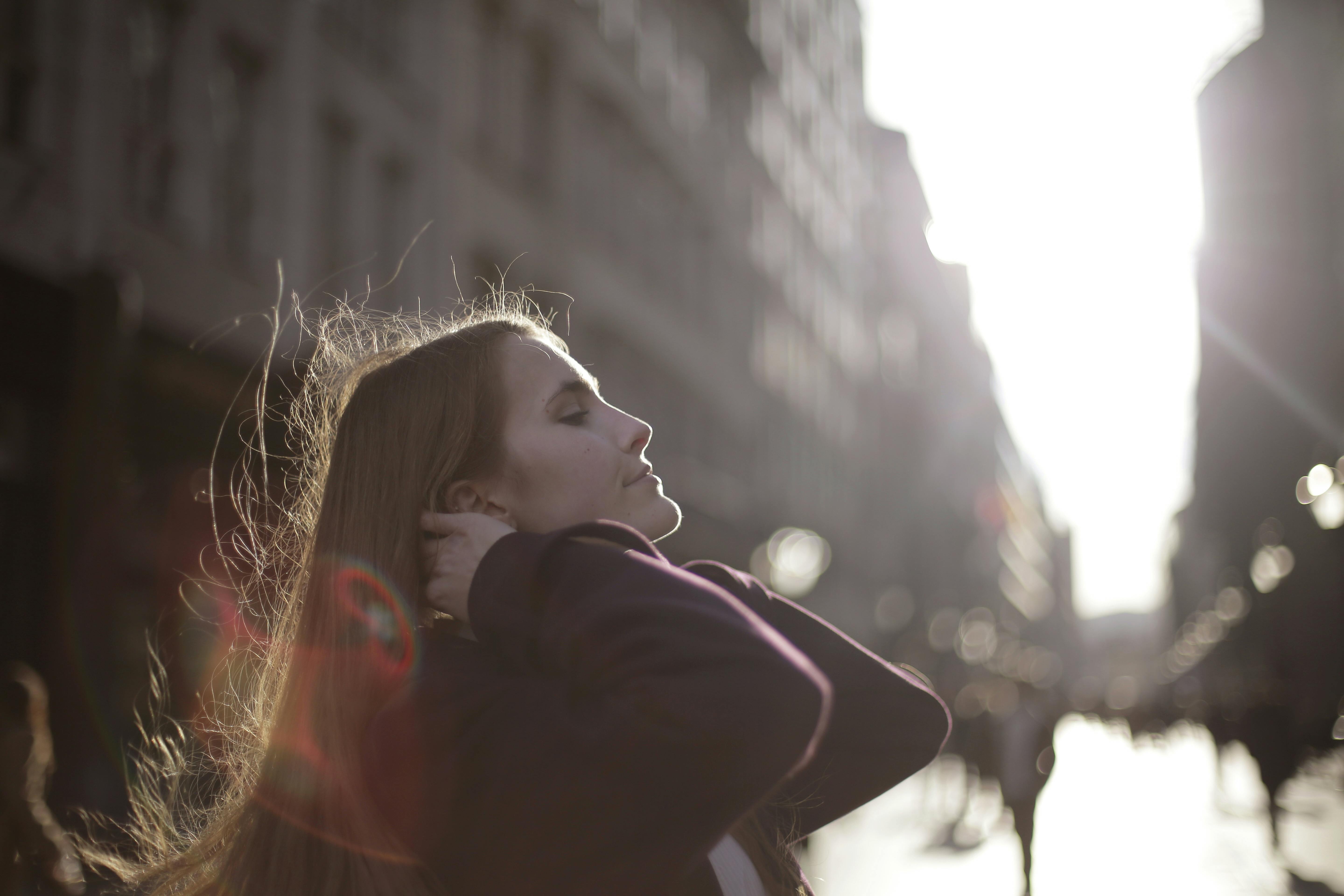 城市街道上，一个女人侧身享受着阳光