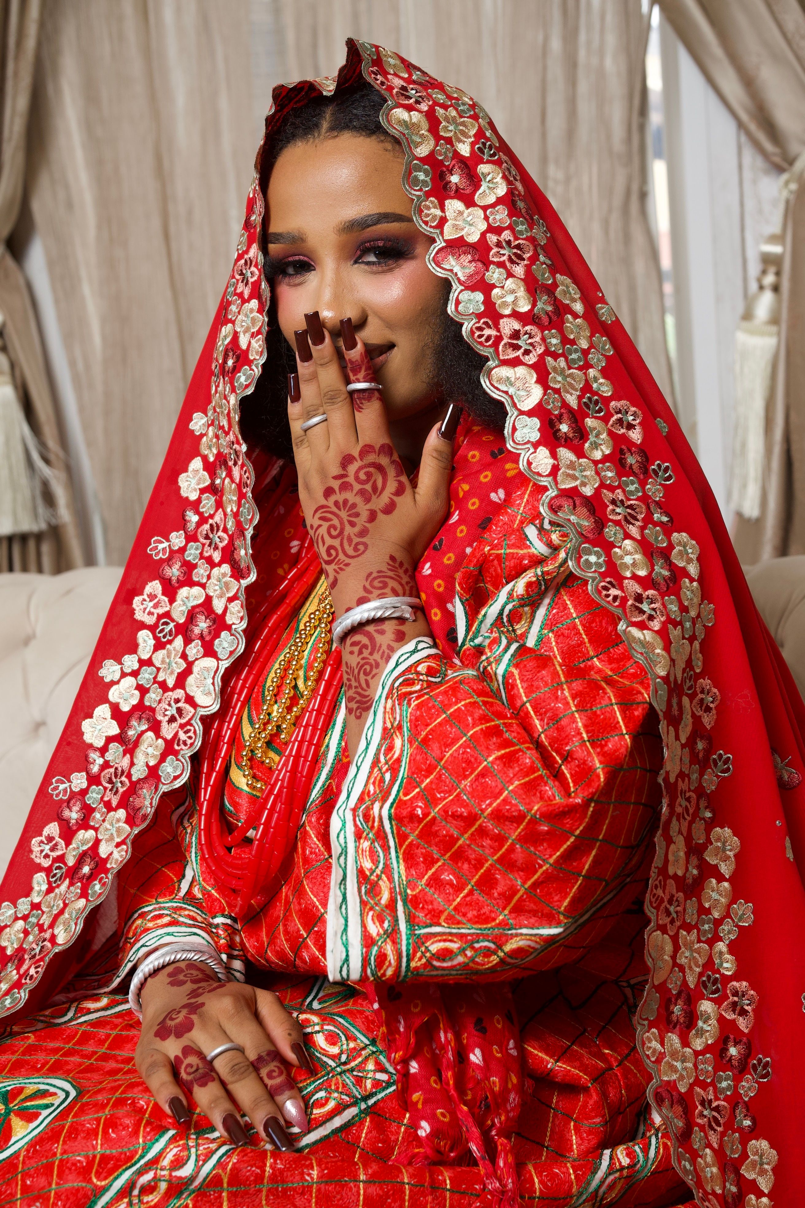 Beautiful Nigerian bride in red traditional dress with intricate henna designs, showcasing cultural elegance.