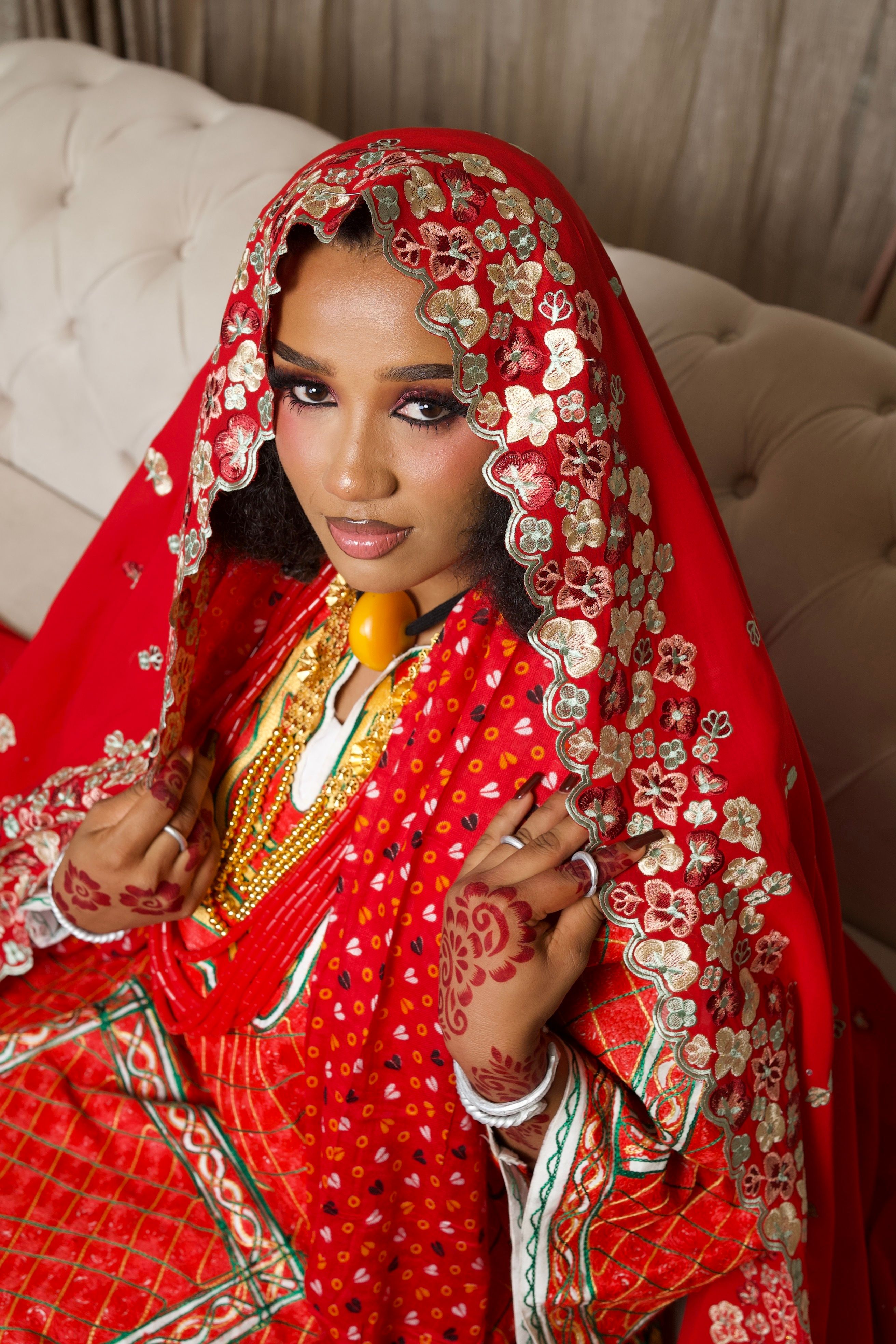 Elegant Nigerian bride in ornate red dress with bridal veil showcasing cultural heritage.