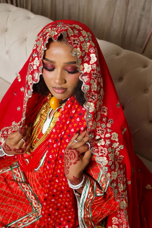 Free Stunning Nigerian bride in red traditional attire with ornate gold jewelry and henna art. Stock Photo