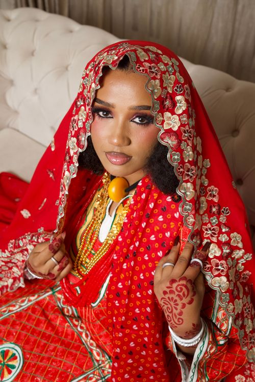 Free Stunning portrait of a Nigerian bride in traditional red attire with intricate henna designs and gold jewelry. Stock Photo