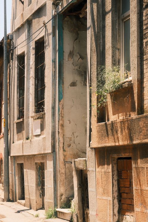 Free Weathered facade of an urban building with visible decay and natural elements. Stock Photo