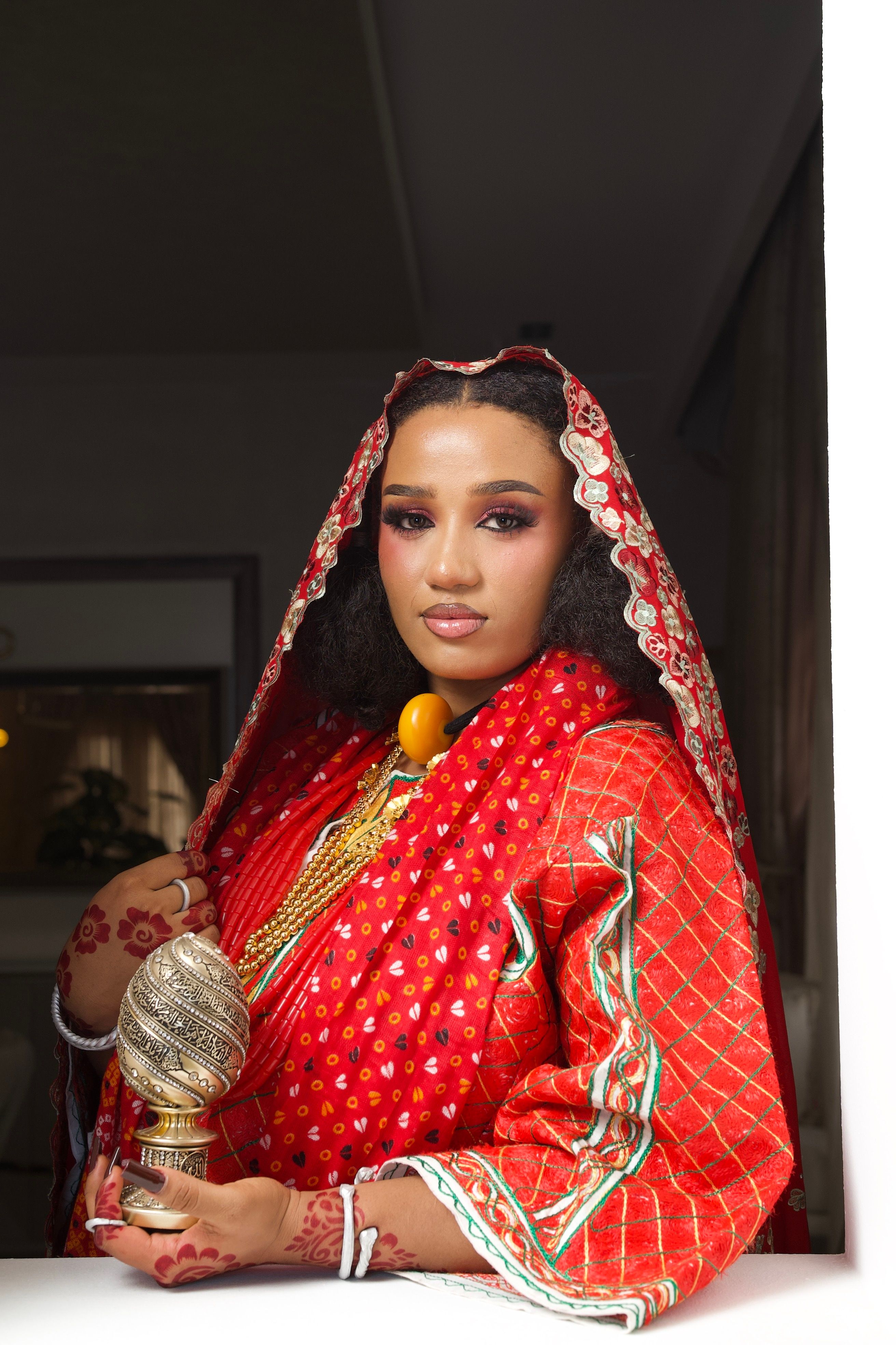 Portrait of an elegant Nigerian bride in traditional red attire, showcasing cultural heritage.