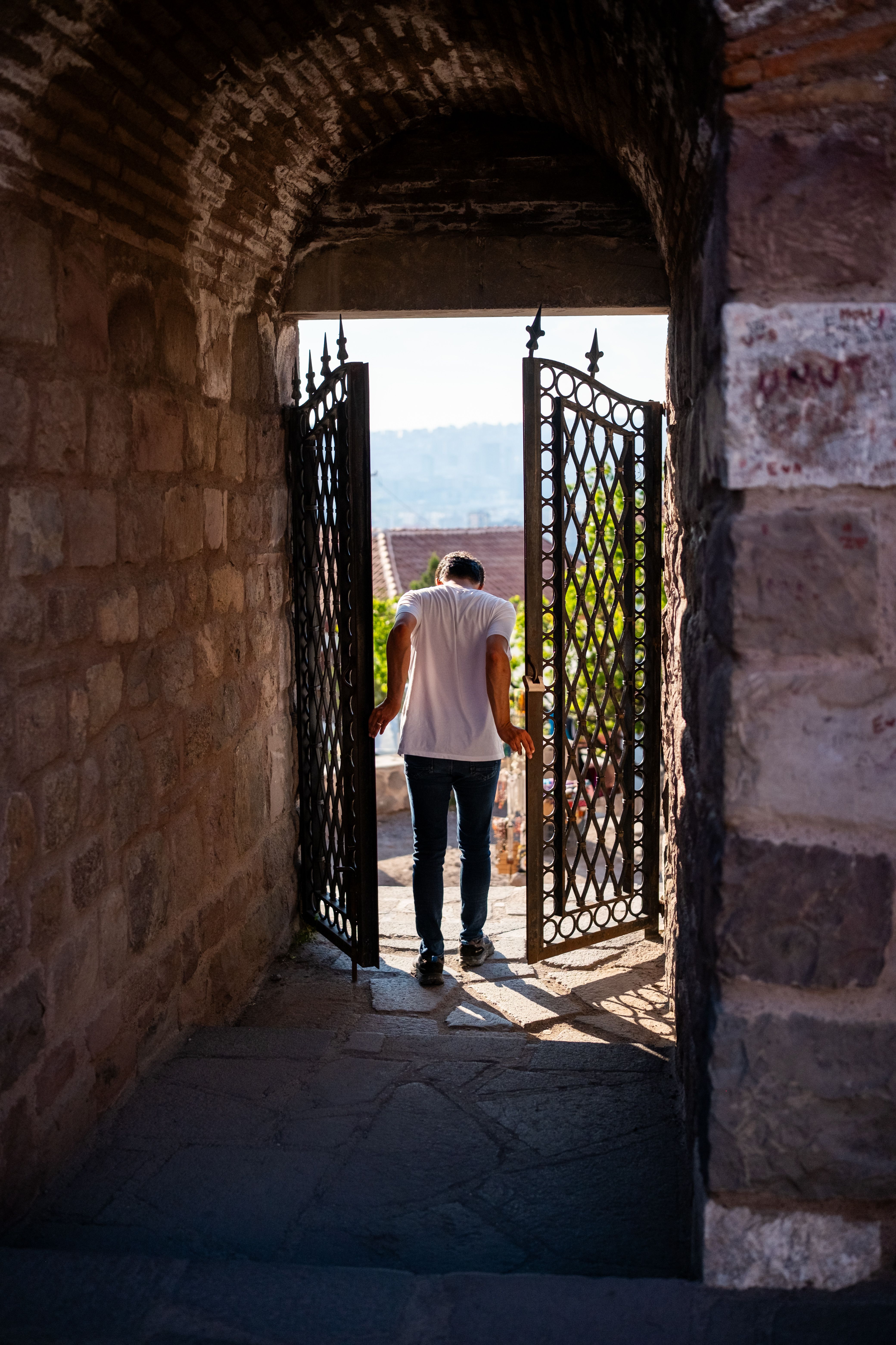 Fotomural Un hombre camina a través de una histórica puerta de piedra en Ankara, Turquía, en un día soleado.