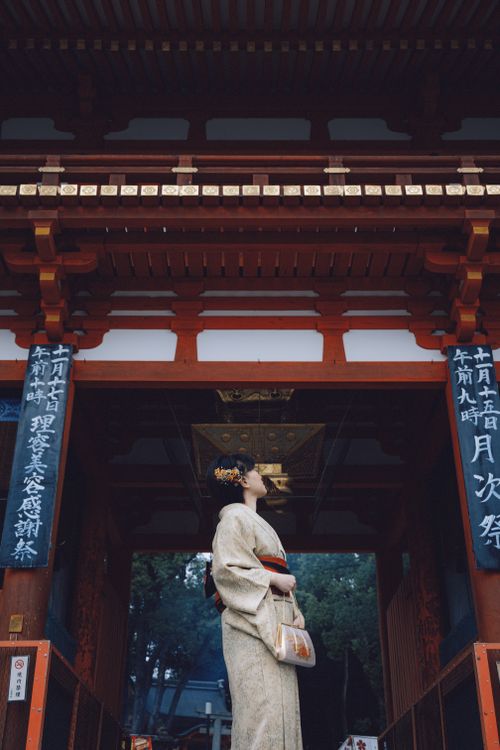 Free A woman in a kimono stands elegantly by a traditional Japanese temple gate, capturing cultural essence. Stock Photo