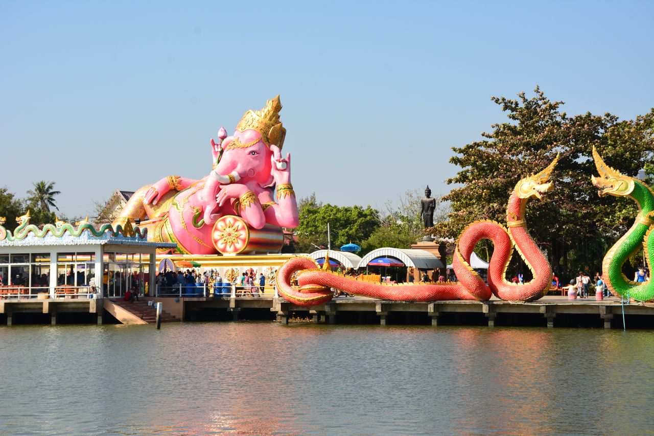giant ganesh and colorful serpent statues by a lake in tambon bang kae